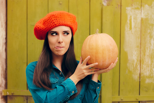 Fall  girl wearing blue jeans outfit and holding a fresh squash
