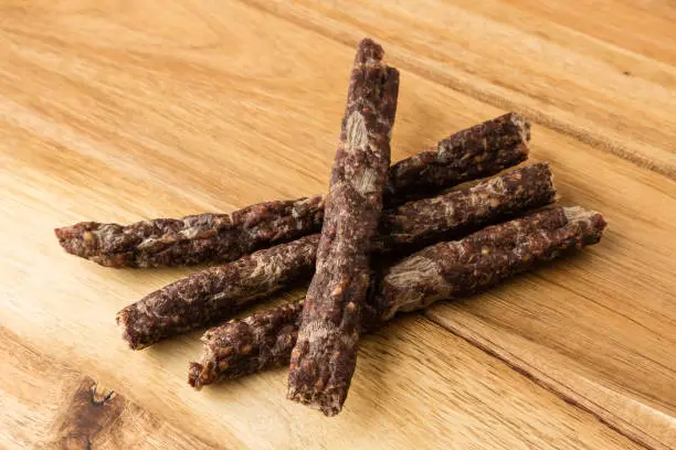 Photo of Droewors (dried meat) on a wooden board, this is a traditional food snack that can be found in South Africa. This image has selective focusing.