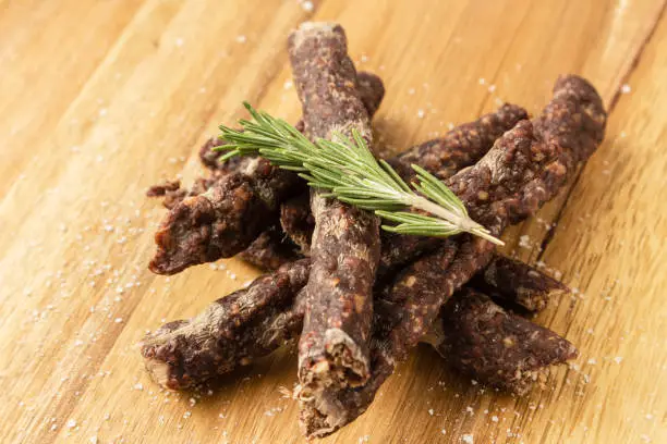 Photo of Droewors (dried meat) on a wooden board, this is a traditional food snack that can be found in South Africa. This image has selective focusing.