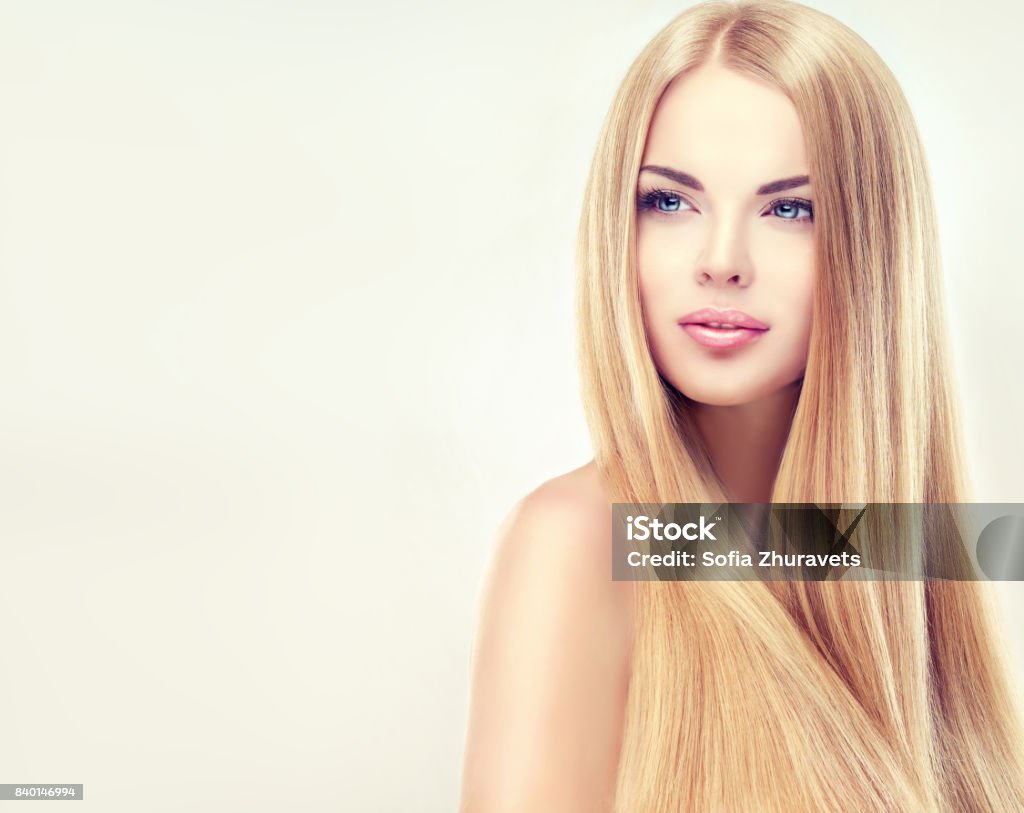 Extremely attractive blonde. Young, blonde haired woman  with long, straight,shiny hair. Young, blonde haired woman  with long, straight, healthy and shiny hair. Beautiful model with long, straight,  hairstyle, delicate make-up and  pale rose lipstick on the lips. Blond Hair Stock Photo