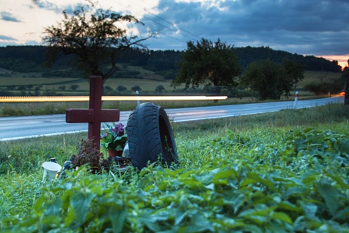 Lights of moving cars on a rural road. Evening in the place of a fatal accident. Place a car accident at the crossroads