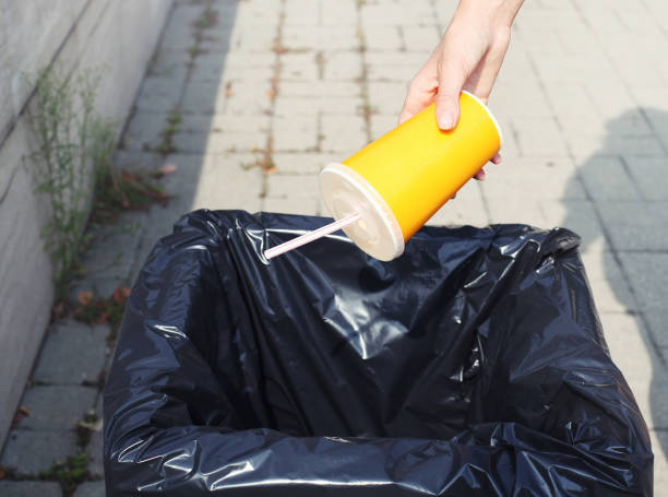 ecología, medio ambiente, reciclaje concepto - lanzamiento de vaso de plástico en la basura en la calle ciudad de la mano - tin can phone fotografías e imágenes de stock