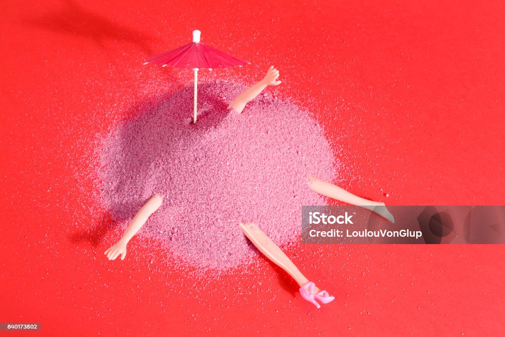 doll and pink sand Arm and leg's doll emerging from a pile of pink sand as if it were hiding. Minimal funny and quirky design still life photography Eccentric Stock Photo