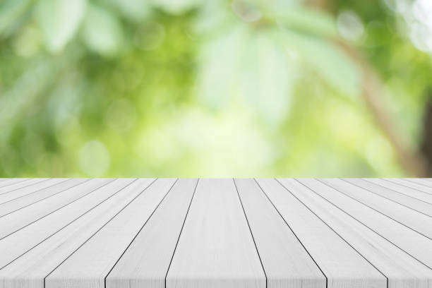 istock Empty white wood table top on nature green blurred background,space for montage show products 840174380