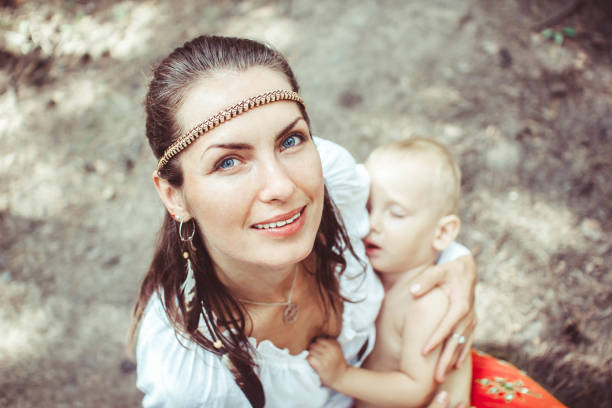 Cute caucasian mother holding her newborn baby outdoor in the woods