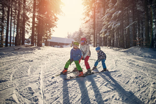 três filhos esquiar num dia de inverno de bonito - skiing snow skiing helmet fun - fotografias e filmes do acervo