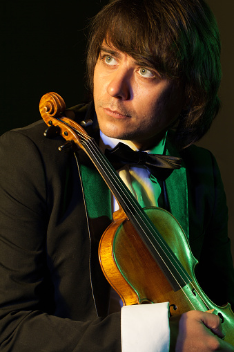 young violinist playing violin in hat and jacket  on  light background
