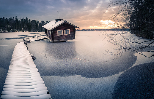 Abandoned cottage with sunset at winter evening in Finland