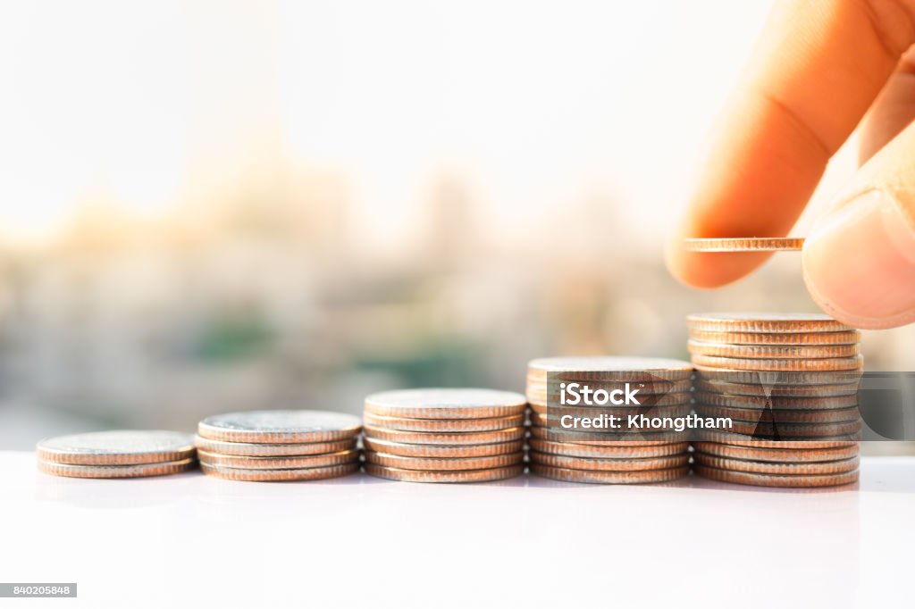 Man's hand put money coins to stack of coins. Money, Financial, Business Growth concept. Coin Stock Photo