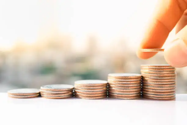 Photo of Man's hand put money coins to stack of coins. Money, Financial, Business Growth concept.