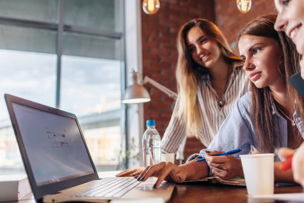istock Three cheerful female college students surfing the internet using laptop together searching the information 840209804