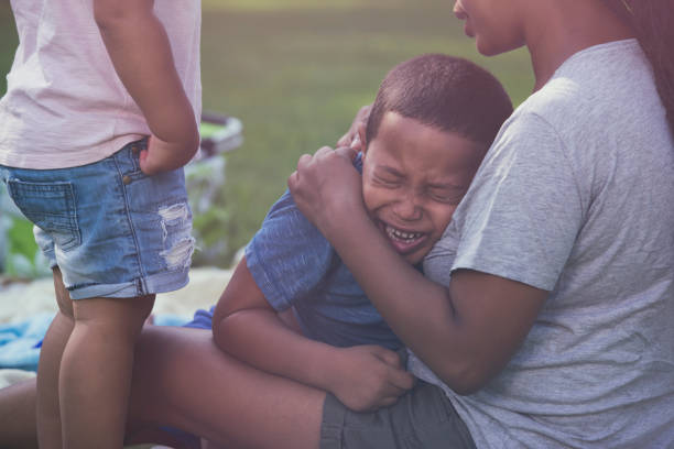 madre consuela a su hijo llorando. - family grass toddler african descent fotografías e imágenes de stock