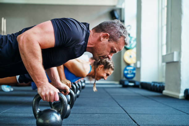 istock Focused man doing pushups on weights in a gym class 840230092
