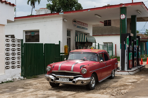 Matanzas: American red Pontiac classic car on the gas station in Matanzas Cuba - Serie Cuba Reportage