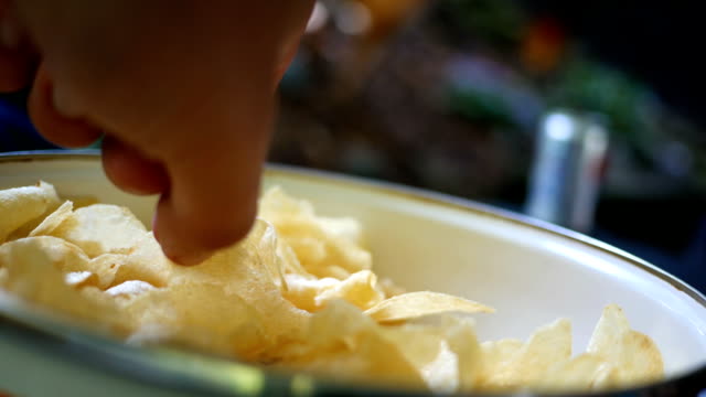 People eating a bowl of chips as snackfood at outdoor backyard party