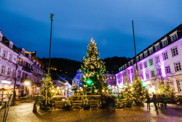 Christmas market with giant artificial christmas trees in historic architecture and blurred people in Heidelberg, Germany. 2016