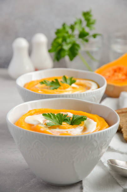 istock Pumpkin soup with cream and parsley on a grey concrete or stone background 840247432