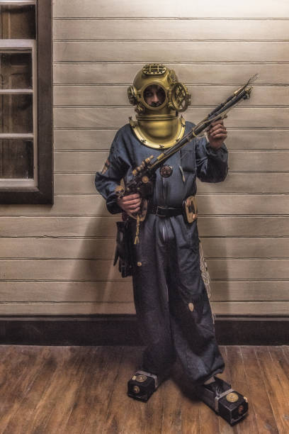 Man wearing an old diving equipment with helmet and holding an underwater weapon Man wearing an old diving equipment with helmet during a Steampunk convention in Paranapiacaba, Sao Paulo, Brazil steampunk pistol pictures stock pictures, royalty-free photos & images