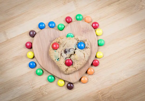 Delicious homemade sweet cookies with colorful chocolate sweets creating a heart shape.