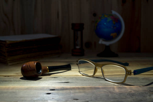 eyeglass and tobacco pipe on wooden table. still life style.