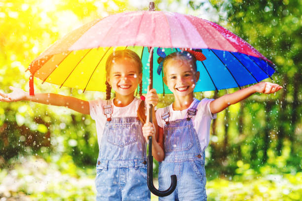 felice divertente sorelle gemelle bambina con ombrello - preschooler portrait family outdoors foto e immagini stock