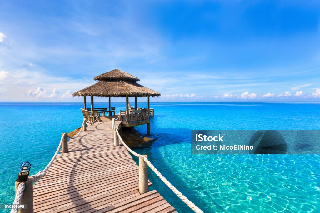 Beautiful summer tropical beach landscape, wooden pier, turquoise sea water Beautiful tropical summer beach landscape, luxurious hotel wooden pier with transparent turquoise sea water Caribbean Stock Photo