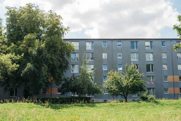 istock grey apartment building with green grass and trees 840280432