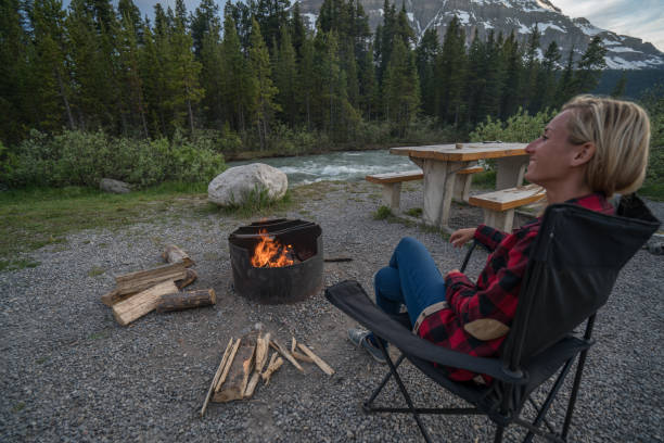 istock Young woman relaxing by the fire at camp 840283398