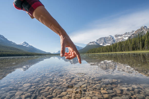istock Finger touches surface of mountain lake 840285892