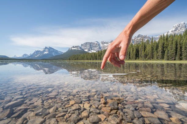 istock Finger touches surface of mountain lake 840285926