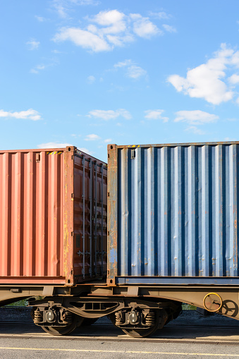 Two containers on a flat car train parked in a shipping yard in the suburbs of Paris, France.