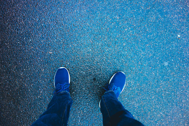istock man looking down to his sport shoes on blue ground 840292410