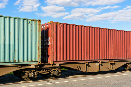 Two containers on a flat car train parked in a shipping yard in the suburbs of Paris, France.