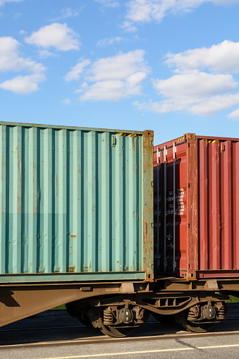 Two containers on a flat car train parked in a shipping yard in the region of Paris, France.