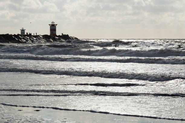 istock Backlighted breakwaters with towers, people, selected focus on people's silhouettes. 840296290