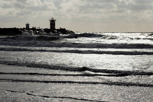 istock Backlighted breakwaters with towers, people, selected focus on foreground waves. 840296298