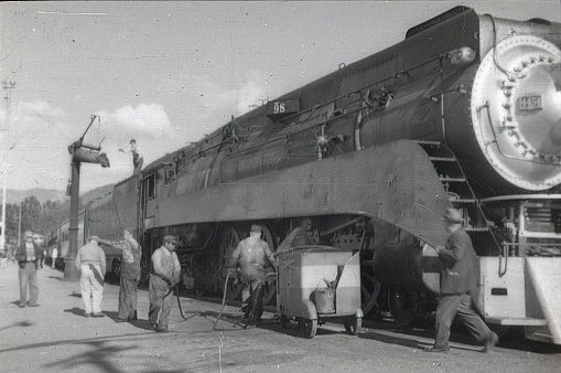 South Virginia, USA, 1952. A train is serviced by a technician at a section of the track in South Virgina.