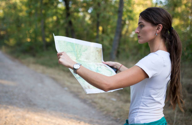 istock Young woman reading a map in the forest 840310016