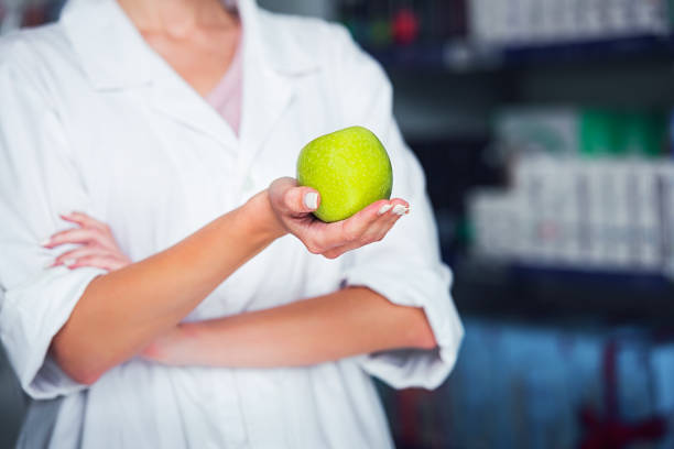 istock close up on a pharmacist's hand holding a green apple 840324104