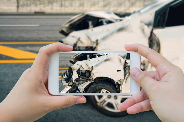 mujer utilizando smartphone tomar fotos del accidente de accidente de coche en la carretera - accidente de automóvil fotos fotografías e imágenes de stock