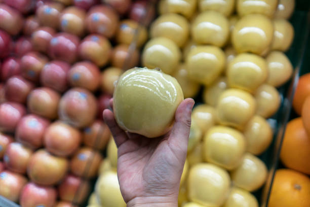 hand holding an apple from a fresh fruits stall