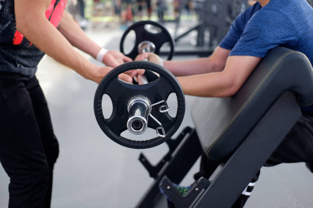 istock Personal trainer helping man bench press in gym. 840392366