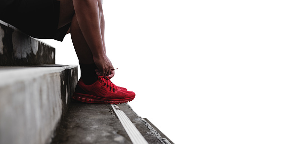 Close-up runner tying shoelace on the steps, isolated on white background with copy space, healthy lifestyle