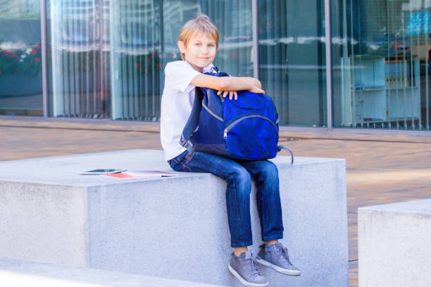 istock Boy sitting with his backpack, books and tablet computer outdoor. 840405356