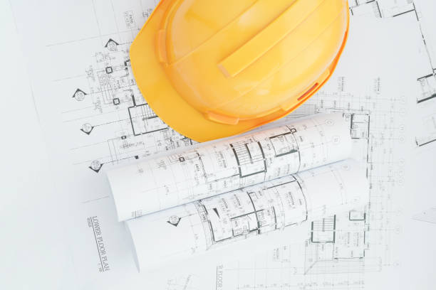 istock architects workplace - architectural blueprints with measuring tape, safety helmet and tools on table. top view 840408210