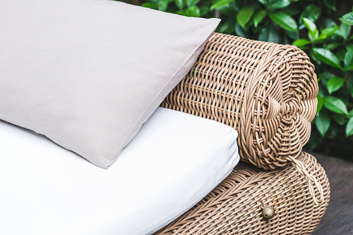 Outdoor wicker bed with white mattress and grey pillow. Clean place for relax and pleasure in hotel garden near pool