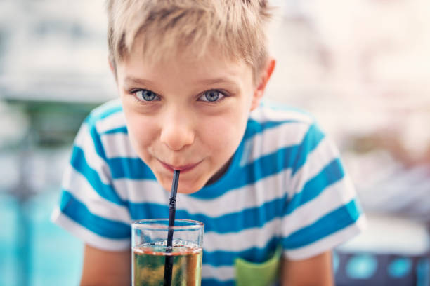 Cute little boy drinking apple juice at hotel restaurant Little boy aged 7 drinking a glass of apple juice. The boy is smiling at the camera while sipping the juice.
 apple juice photos stock pictures, royalty-free photos & images