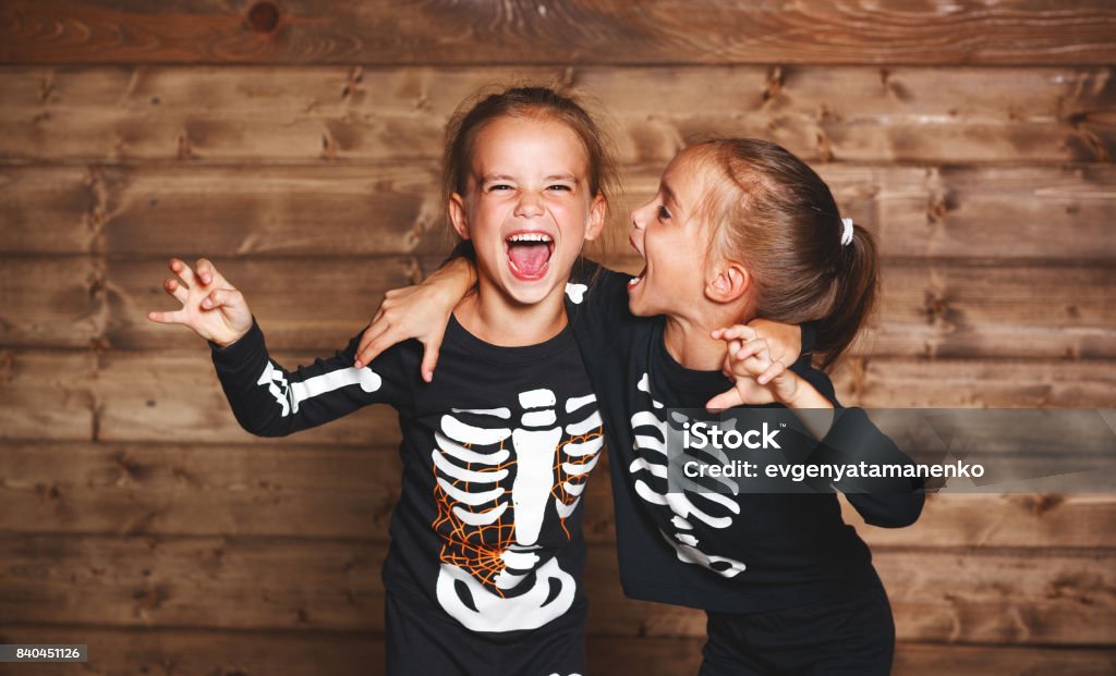 holiday halloween. funny funny sisters twins children in carnival costumes skeleton  on wooden holiday halloween. funny funny sisters twins children in carnival costumes skeleton on a wooden background Halloween Stock Photo