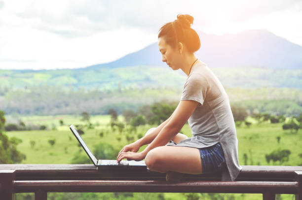 jovem mulher usando um computador no parque - laptop computer grass nature - fotografias e filmes do acervo