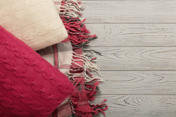 istock Knitted pillows and plaid on a light wooden background. 840458706